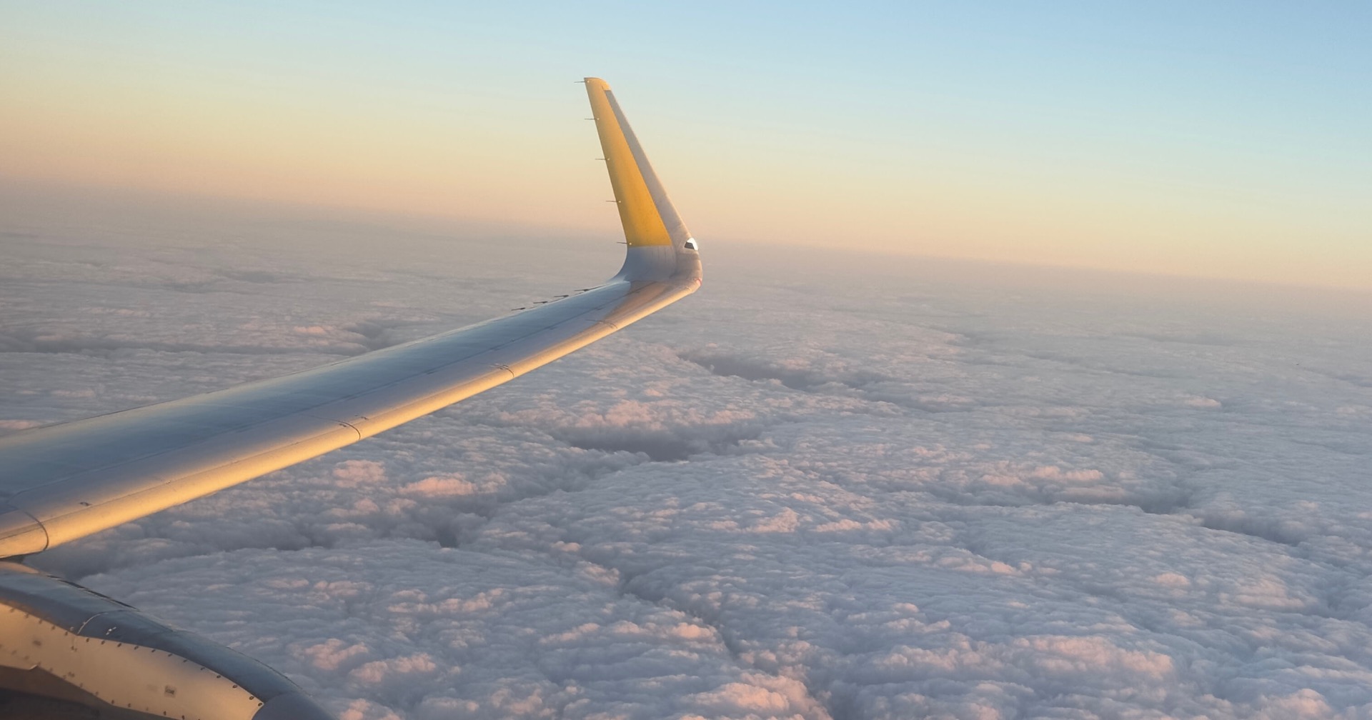 Vista del ala de un avión sobre un mar de nubes al amanecer